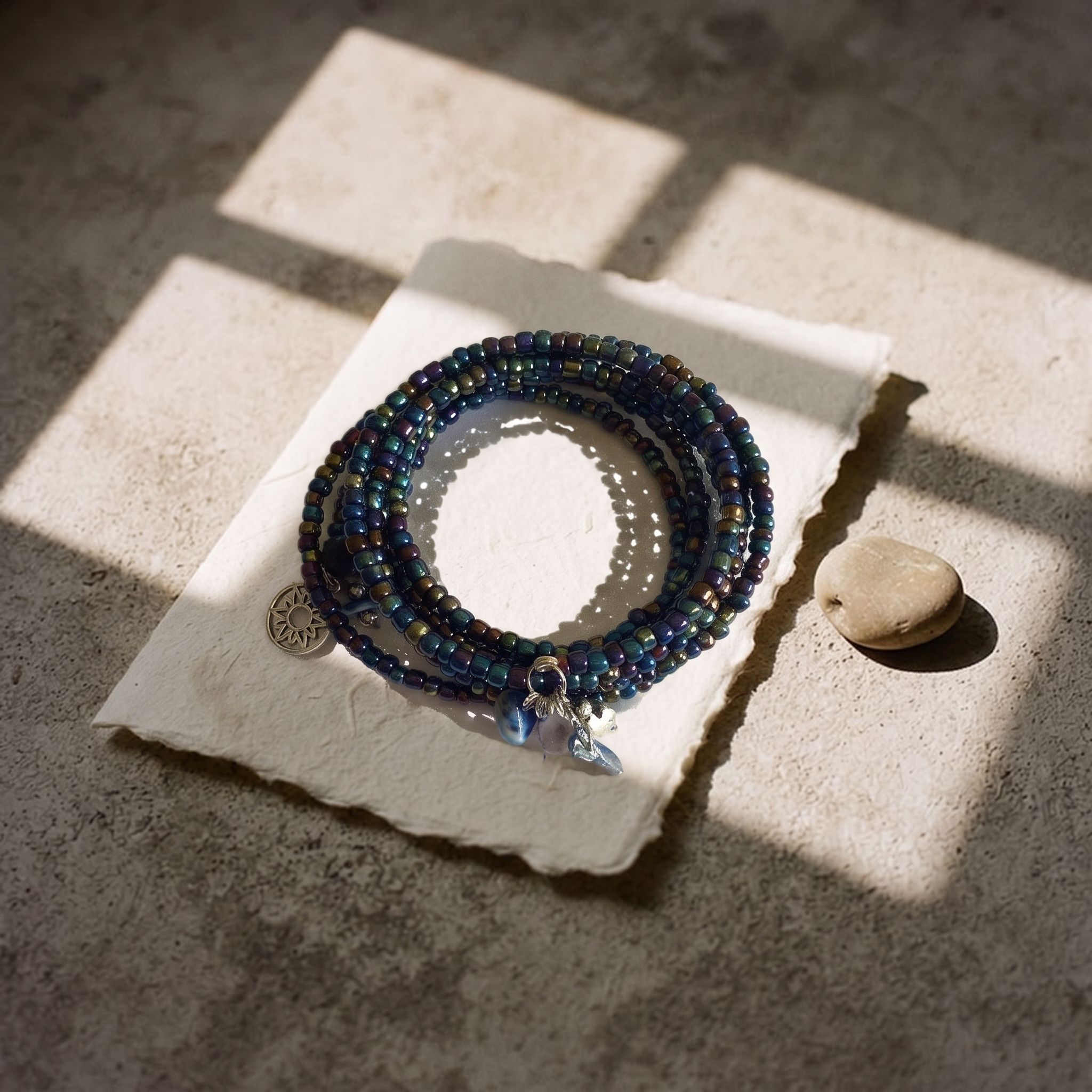 Pulsera azul enrollada sobre papel, bajo la luz de una ventana