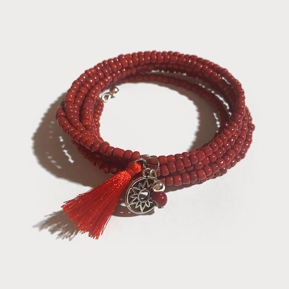 Pulsera Ascua en espiral de cuentas rojas con un dije de pewter y una borla roja